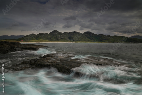 Sanna Bay, highlands, scotland with blurred water as foreground and mountain background.