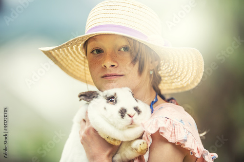Young kid in a hat holding a scared rabbit in hands. Rabbit is scared to death probably © weyo