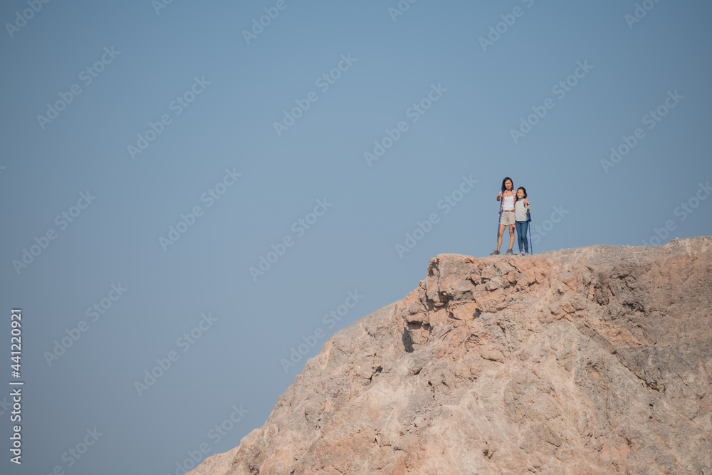 family travel- hikers with backpack looking at mountains view, mother with child at the day time, little girl with mother trekking on red trail, Concept of friendly family.