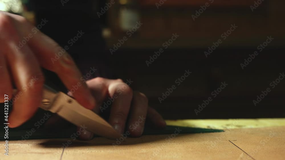 Leather craftsman making at work. Close up pan of his hands cutting leather using a small knife and a bracket Leather craftsman making at work. Close up pan of his hands cutting leather using a small knife and a bracket