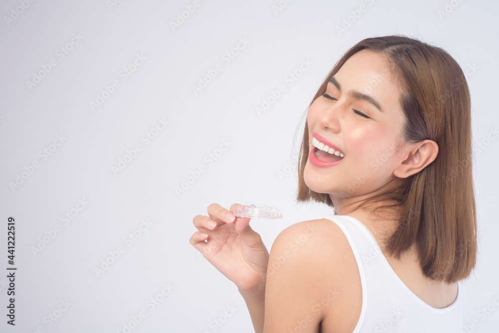 Young smiling woman holding invisalign braces over white background studio, dental healthcare and Orthodontic concept. Young smiling woman holding invisalign braces over white background studio, dental healthcare and Orthodontic concept.