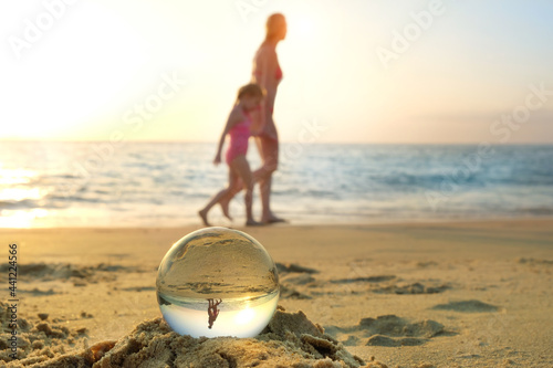 glass ball and people silhouets on sea beach. mother and kid on tropical ocean natural background. summer vacation, relax time, travel concept.  photo