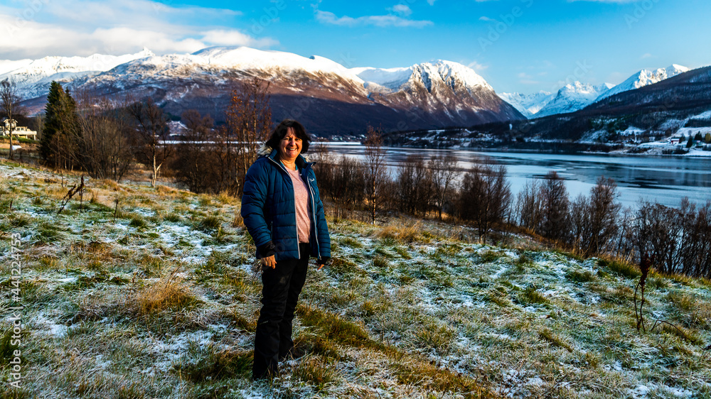 Ingeborg Kuhn auf dem frisch verschneiten Hügel über dem Fjord, mit Aussicht in die Berge von Troms in der Nähe von Tromsö, Norwegen. Frau geniesst die Aussicht am sonnigen Herbsttag