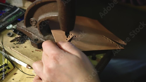 Leather craftsman at work. Top view Close up of his hands using a hand rivet press in order to puncture leather