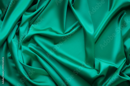 Elegant soft abstract green background. Delicate silk waved fabric with copy space for design projects