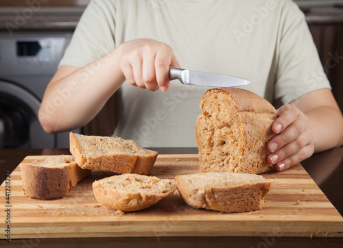 Young woman cutting bread with knife.