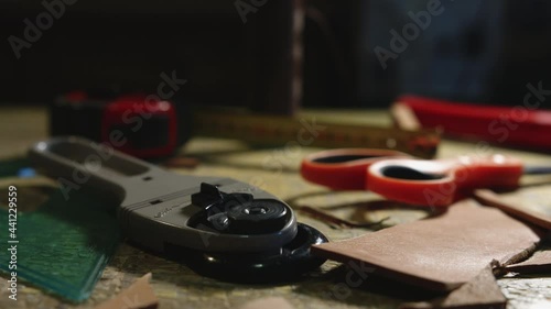 Leather craftsman at work. Close up pan of his ready to use work tools on his work table