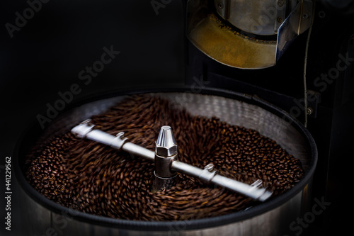 fresh coffee beans and roasted spinning cover professional machine close up and selective focus on dark