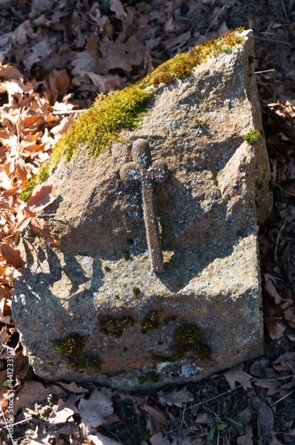 Small simple cross on stone with moss in old churchyard. Winniki (village in Lobez County, West Pomeranian Voivodeship), Poland.