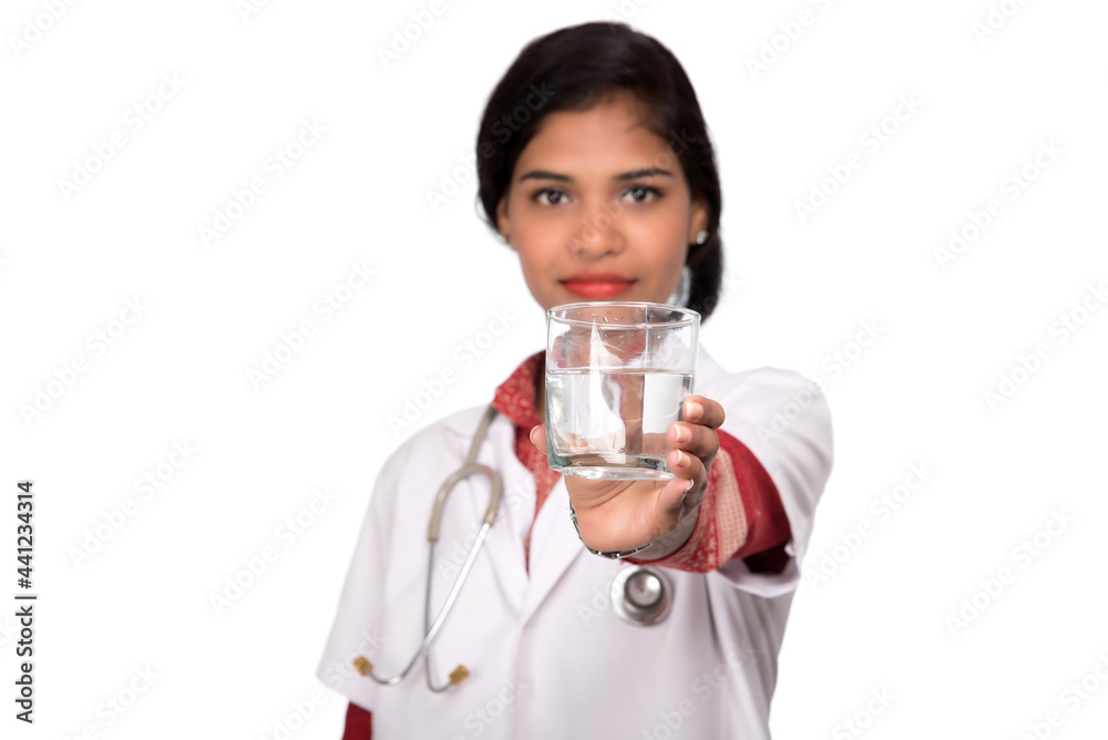 Healthy eating or lifestyle concept: Smiling female doctor holding a glass of clear fresh water Healthy eating or lifestyle concept: Smiling female doctor holding a glass of clear fresh water