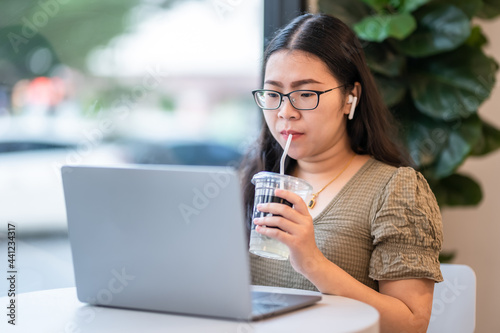 Happy of asian freelance people Businesswoman wearing wireless earphones with sucking coffee working with laptop computer,Notebook and smartphone at the cafe,Business Lifestyle communication