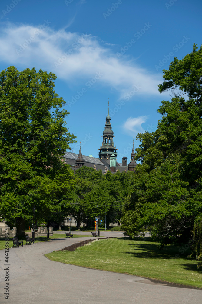 Park view with trees and a tower on a gothic house in Stockholm