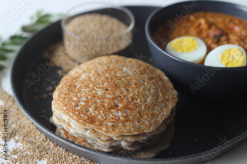 Kodo millet pancakes served with egg roast. Pancake is made with a fermented batter of kodo millet, flattened rice, coconut. Egg roast is Boiled egg in a spicy gravy of onions, tomatoes, spices