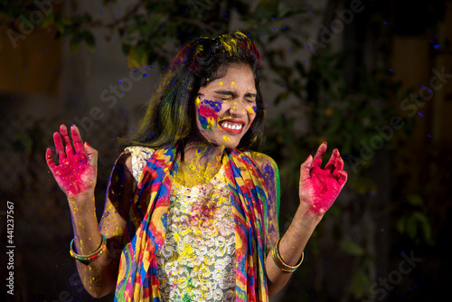 Young girl showing colorful palm and celebrating Holi with color splash