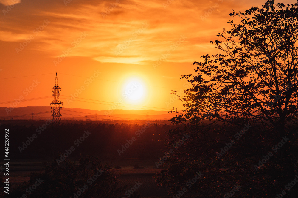 Sonnenuntergang mit orange farbenen Himmel und einem Strommast