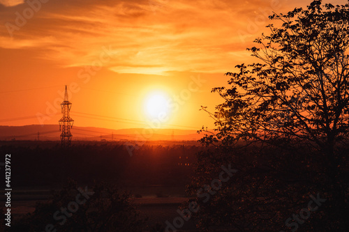 Sonnenuntergang mit orange farbenen Himmel und einem Strommast
