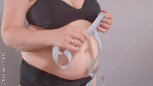 A woman holds a measuring meter in her hands and shows body fat with her hands. Admitting excess weight before starting workouts. photo