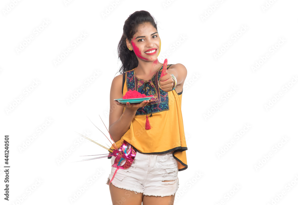 Beautiful young girl holding powdered color in plate with carnival mask on the occasion of Holi festival. Beautiful young girl holding powdered color in plate with carnival mask on the occasion of Holi festival.