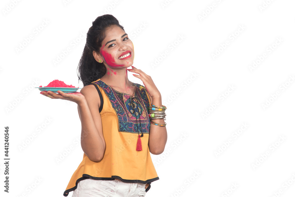Beautiful young girl holding powdered color on a plate and enjoying colors on the occasion of the Holi festival. Beautiful young girl holding powdered color on a plate and enjoying colors on the occasion of the Holi festival.