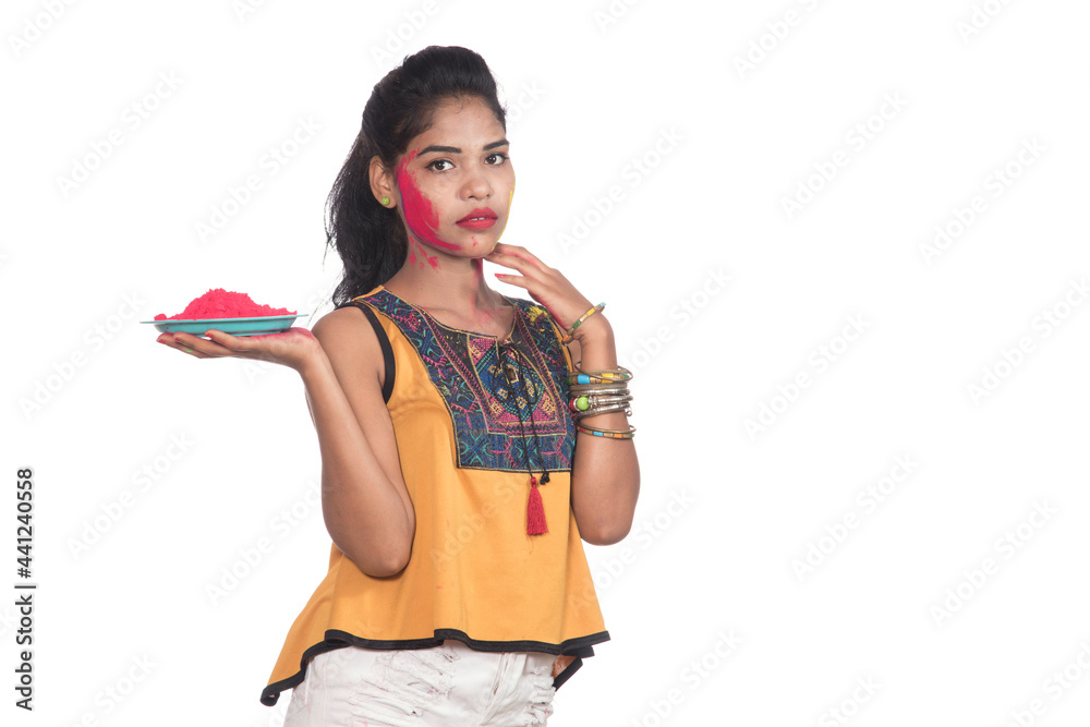 Beautiful young girl holding powdered color on a plate and enjoying colors on the occasion of the Holi festival. Beautiful young girl holding powdered color on a plate and enjoying colors on the occasion of the Holi festival.