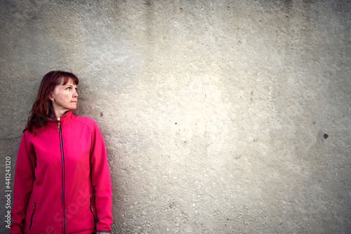 Caucasian woman on a background of a concrete wall looking to the side