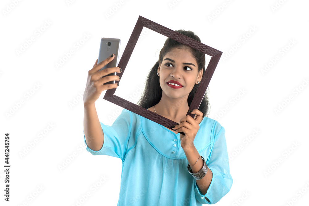 Young Indian girl using a mobile phone or smartphone with photo frame on a white background Young Indian girl using a mobile phone or smartphone with photo frame on a white background
