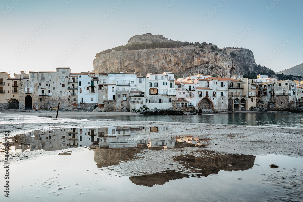 Sunrise on beach in Cefalu, Sicily, Italy, old town panoramic view with colorful waterfront houses, sea and La Rocca cliff.Attractive summer cityscape,traveling concept background.Italian vacation.