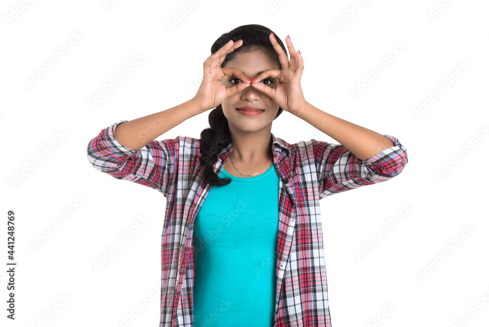 young woman looking at camera through fingers in ok gesture. Imitating binoculars over white background young woman looking at camera through fingers in ok gesture. Imitating binoculars over white background
