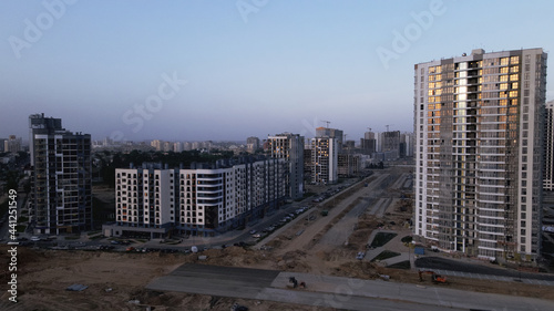 Construction of a new city block. New construction of modern multi-storey buildings. The setting sun is reflected in the windows of the houses. Aerial photography.