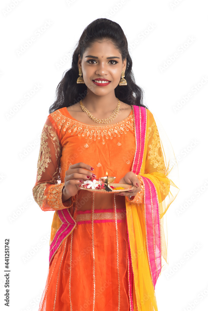 Beautiful Indian young girl holding pooja thali or performing worship on a white background Beautiful Indian young girl holding pooja thali or performing worship on a white background