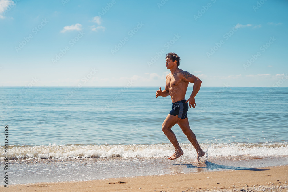 Young muscular guy, with a bare torso running along the beach Young muscular guy, with a bare torso running along the beach