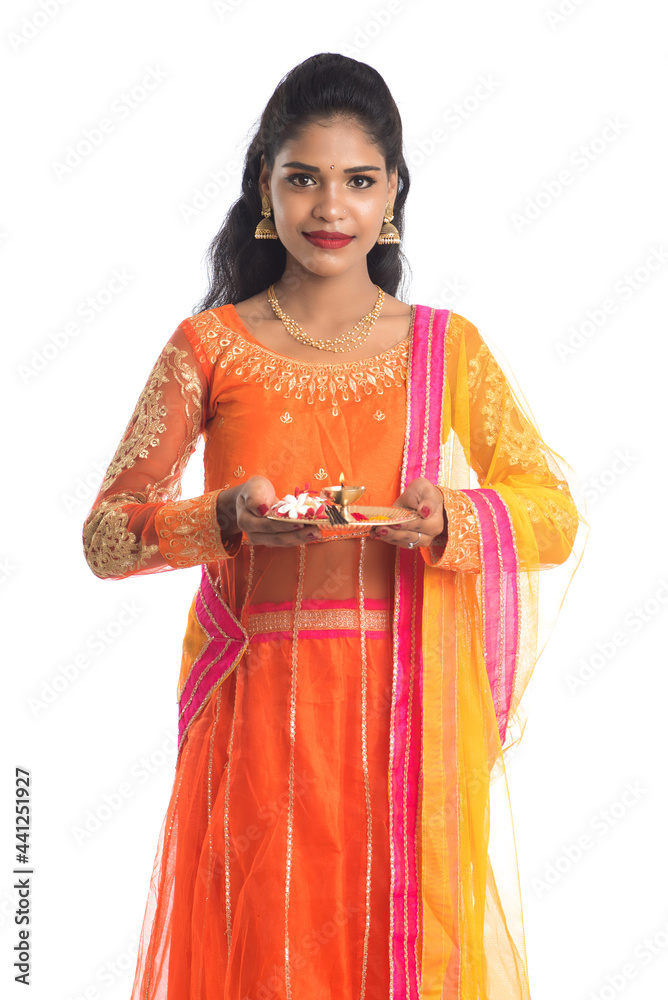 Beautiful Indian young girl holding pooja thali or performing worship on a white background