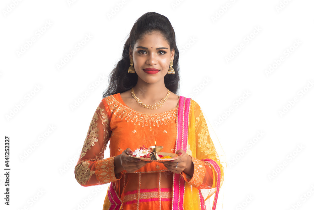 Beautiful Indian young girl holding pooja thali or performing worship on a white background Beautiful Indian young girl holding pooja thali or performing worship on a white background