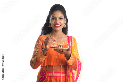 Beautiful Indian young girl holding pooja thali or performing worship on a white background