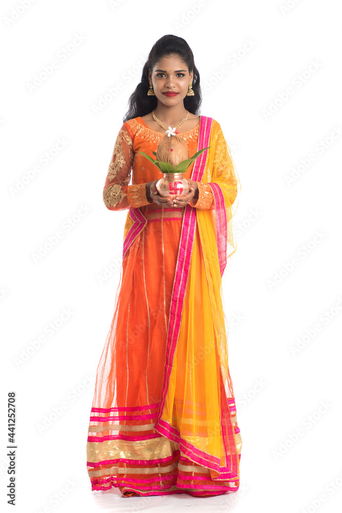 Indian Woman holding a traditional copper kalash, Indian Festival, copper kalash with coconut and mango leaf with floral decoration, essential in hindu puja. Indian Woman holding a traditional copper kalash, Indian Festival, copper kalash with coconut and mango leaf with floral decoration, essential in hindu puja.
