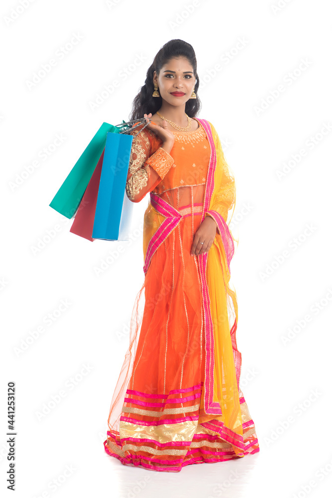 Beautiful Indian young girl holding shopping bags while wearing traditional ethnic wear. Isolated on a white background