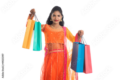 Beautiful Indian young girl holding shopping bags while wearing traditional ethnic wear. Isolated on a white background