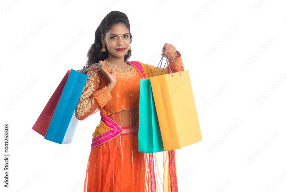 Beautiful Indian young girl holding shopping bags while wearing traditional ethnic wear. Isolated on a white background Beautiful Indian young girl holding shopping bags while wearing traditional ethnic wear. Isolated on a white background