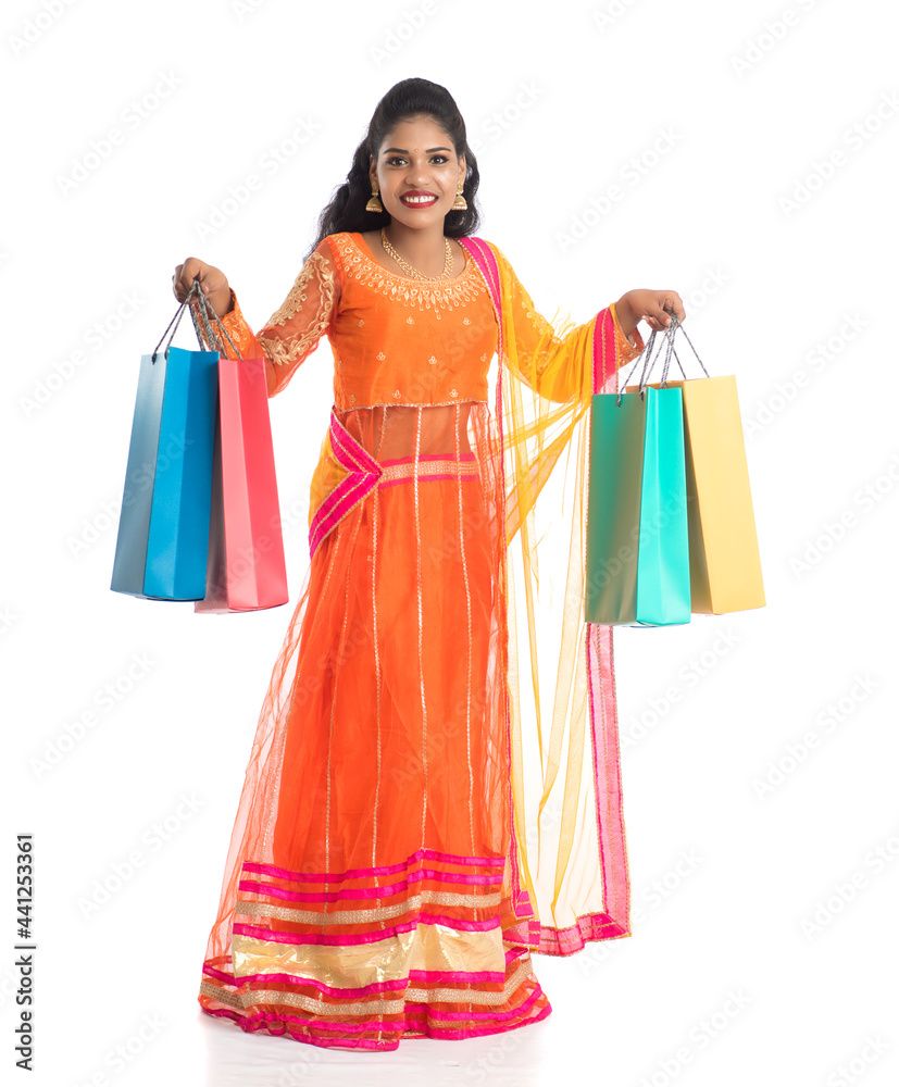 Beautiful Indian young girl holding shopping bags while wearing traditional ethnic wear. Isolated on a white background
