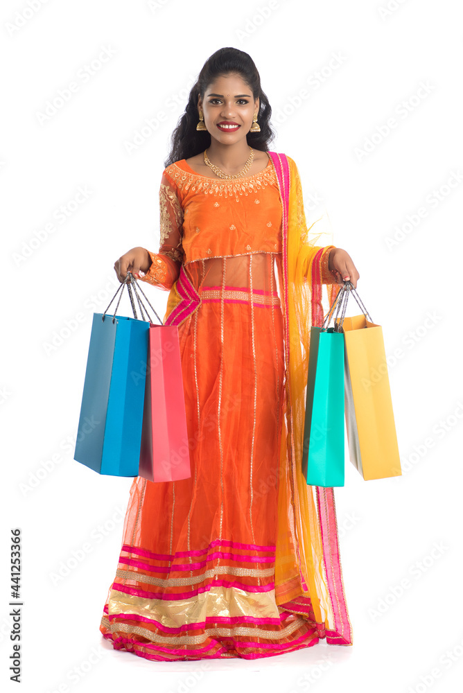 Beautiful Indian young girl holding shopping bags while wearing traditional ethnic wear. Isolated on a white background Beautiful Indian young girl holding shopping bags while wearing traditional ethnic wear. Isolated on a white background