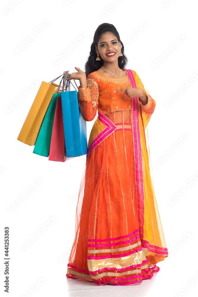 Beautiful Indian young girl holding shopping bags while wearing traditional ethnic wear. Isolated on a white background Beautiful Indian young girl holding shopping bags while wearing traditional ethnic wear. Isolated on a white background