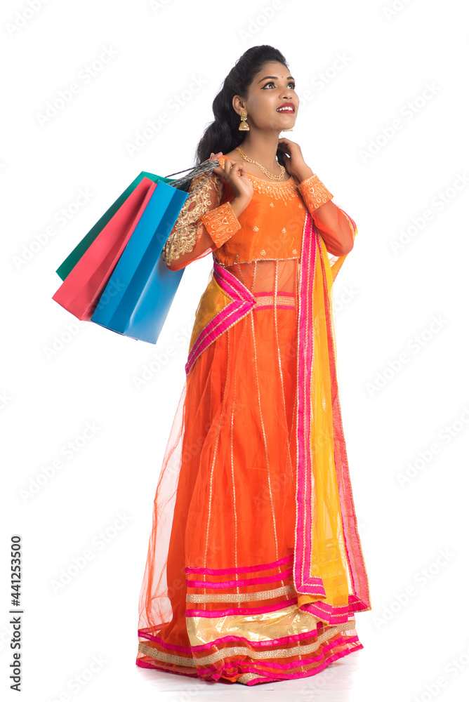 Beautiful Indian young girl holding shopping bags while wearing traditional ethnic wear. Isolated on a white background Beautiful Indian young girl holding shopping bags while wearing traditional ethnic wear. Isolated on a white background