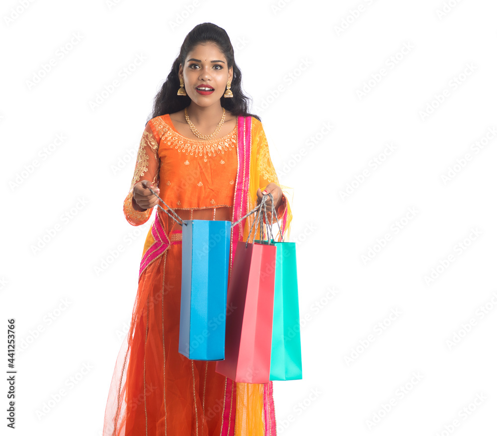 Beautiful Indian young girl holding shopping bags while wearing traditional ethnic wear. Isolated on a white background Beautiful Indian young girl holding shopping bags while wearing traditional ethnic wear. Isolated on a white background