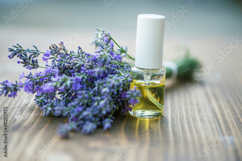 Bottle of Lavender essential oil with fresh lavender flowers on wooden table, aromatherapy spa massage concept. Lavendula oleum