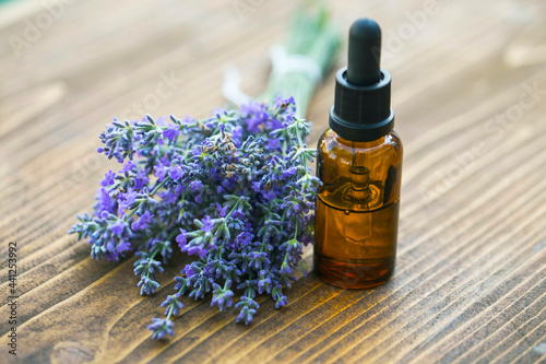 Bottle of Lavender essential oil with fresh lavender flowers on wooden table, aromatherapy spa massage concept. Lavendula oleum
