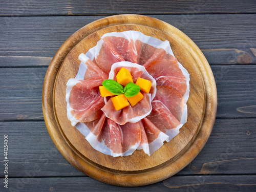 Plate with raw ham, flat lay, top view. Prosciutto with melon. Round shape.