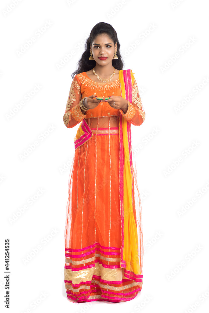 Portrait of a Indian Traditional Girl holding Diya, Girl Celebrating Diwali or Deepavali with holding oil lamp during festival of light on white background