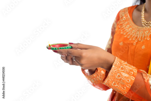 Portrait of a Indian Traditional Girl holding Diya, Girl Celebrating Diwali or Deepavali with holding oil lamp during festival of light on white background