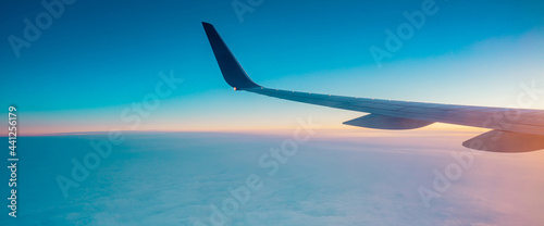 Top view from inside window airplane of a sunset sky and wing