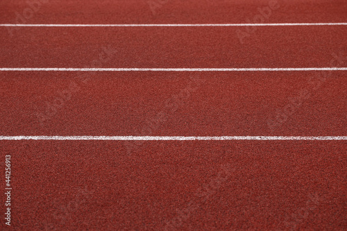 Red racing track with parallel white lines in stadium rubber background